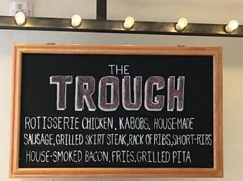 for $250, you can order “The Trough” presenting rotisserie chicken , house-made sausages, grilled skirt steak, short -ribs, house-smoked bacon, grilled pita, topped with seasoned fries on a roughly 3 foot long butcher block.
