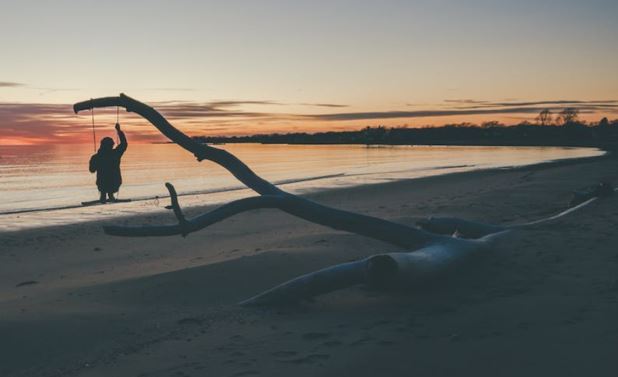 Silhouette of a person on a swing at sunset on a beach